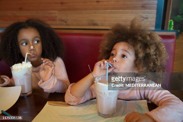 ethnic kid sisters drinking smoothie - tomando sorvete imagens e fotografias de stock