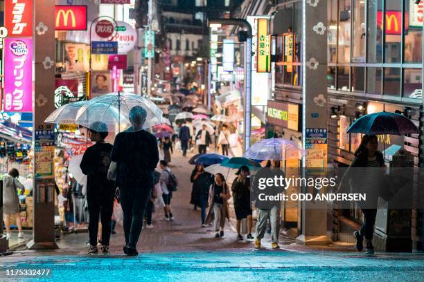 People use umbrellas to shelter from the rain walking along Takeshita Street in Tokyo's Harajuku district on October 11, 2019. - Japan braced on...