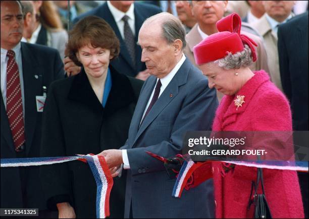 French President François Mitterrand cuts the ribbon at the terminal "France" in Coquelles, Pas de Calais, 6 mai 1994 as his wife Danielle and Queen...