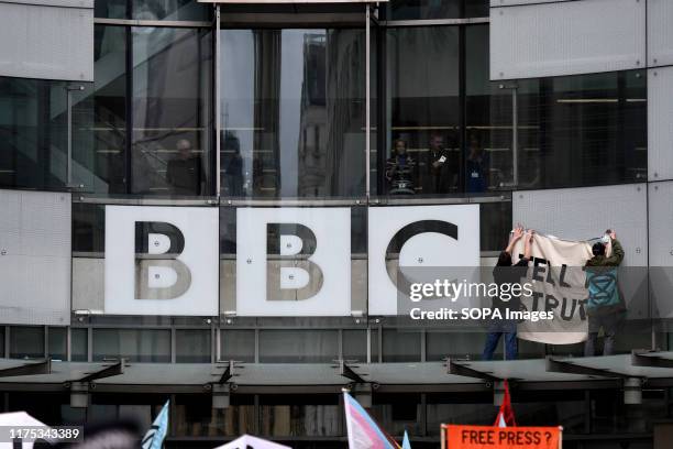 Environmental activists hang a banner on the roof top of the BBC glass entrance during the demonstration. Extinction Rebellion environmental...