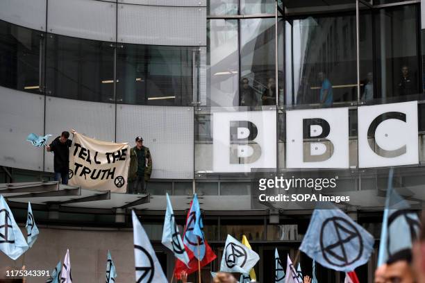 Environmental activists hold a banner with an Extinction Rebellion flag on the roof top of the BBC glass entrance during the demonstration....