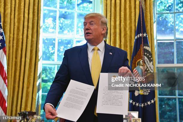 President Donald Trump shows a letter from Chinese President Xi Jinping as he announces and initial deal with China while meeting the special Envoy...