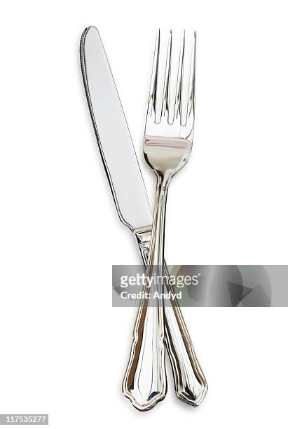 silver fork sitting across a silver knife - tafelmes stockfoto's en -beelden