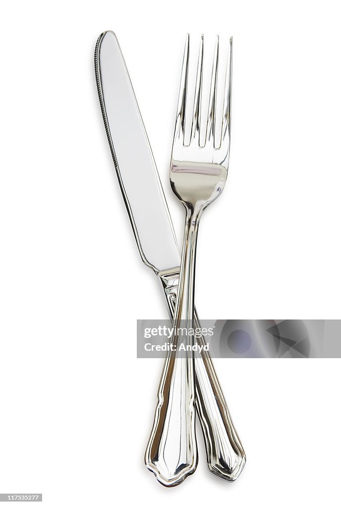 Silver fork sitting across a silver knife