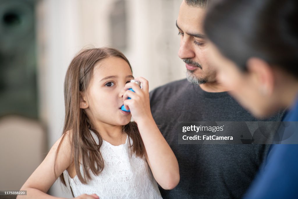 Förskoleåldern flicka med astma lär sig att använda en inhalator