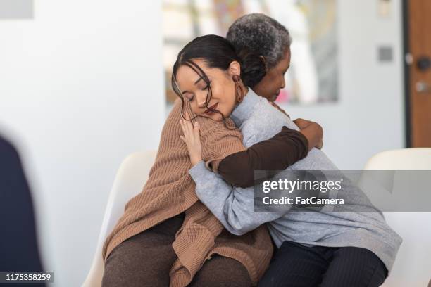 supportive women hug while attending a group therapy session - redemption stock pictures, royalty-free photos & images