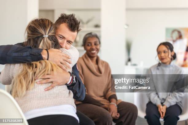 husband and wife hug in group therapy session - addiction recovery stock pictures, royalty-free photos & images