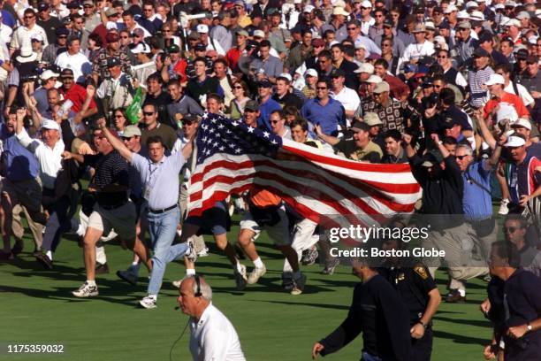 Fans storm the 18th fairway following the last twosome at the 33rd Ryder Cup Matches in Brookline, MA on Sept. 26, 1999. The US team prematurely...