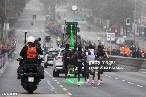 Kenya's Eliud Kipchoge , accompanied by pacemakers and a car in front of them setting the pace with laser beams, takes the start of his attempt to...