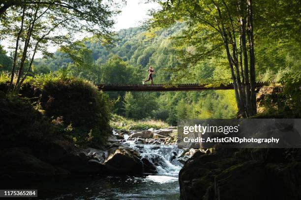 vrouw loopt over brug in de natuur. - voetgangersbrug stockfoto's en -beelden