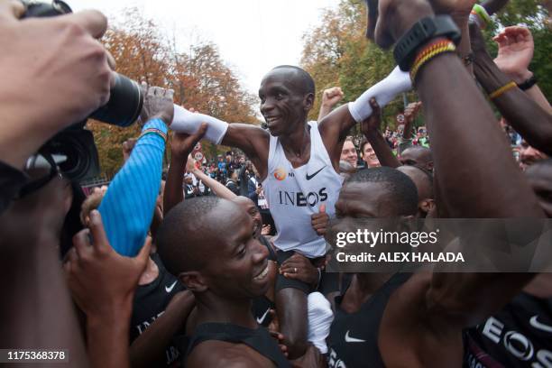 Kenya's Eliud Kipchoge is carried in triumph after crossing the finish line at the end of his attempt to bust the mythical two-hour barrier for the...