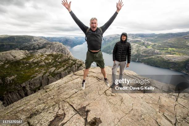 mature man star jumping on preikestolen (pulpit rock) - father son outdoor celebration photos et images de collection