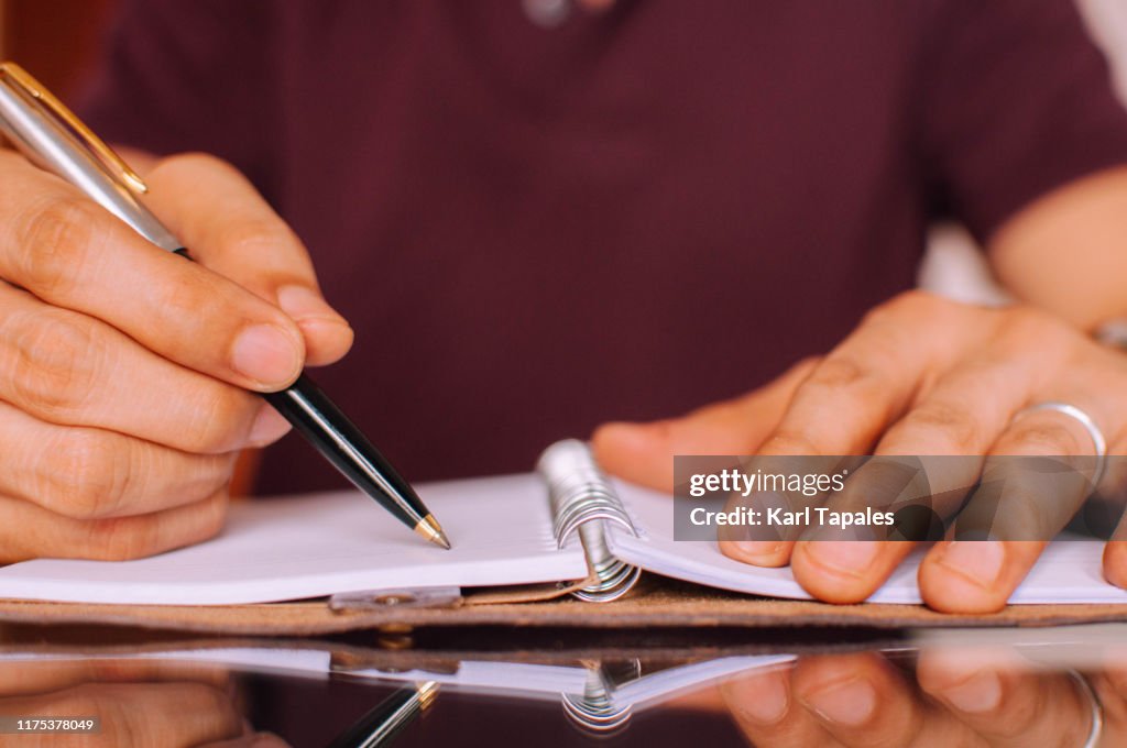 A Person Was Writing A Will To Distribute His Wealth A Young Person Is Writing On His Personal Organizer High-Res Stock