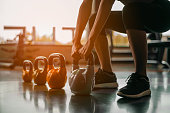 Woman in exercise gear standing in a row holding dumbbells during an exercise class at the gym.Fitness training with kettlebell in sport gym.