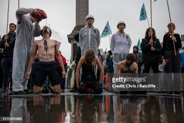 Extinction Rebellion activists pour fake oil over each other as they continue to demonstrate for the sixth day running in Trafalgar Square on October...