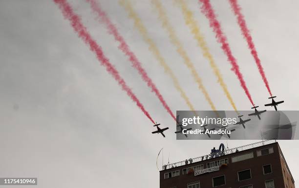 Spanish Air Force's 'Patrulla Aguila' planes leave trails forming the Spanish flag's colours in the sky during the National Day military parade in...