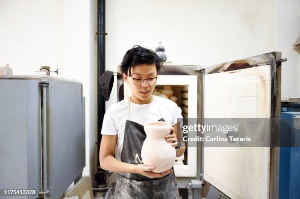 portrait of an asian woman unloading a kiln - kiln stock pictures, royalty-free photos & images