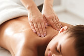 Young woman enjoying therapeutic neck massage in spa