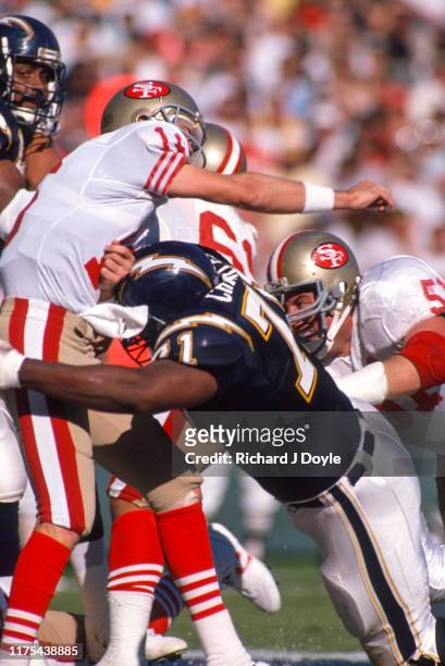 Joe Montana takes a hit after releasing the ball by a S.D. Charger defender. San Francisco 49ers 48 vs San Diego Chargers 10 at Jack Murphy Stadium...