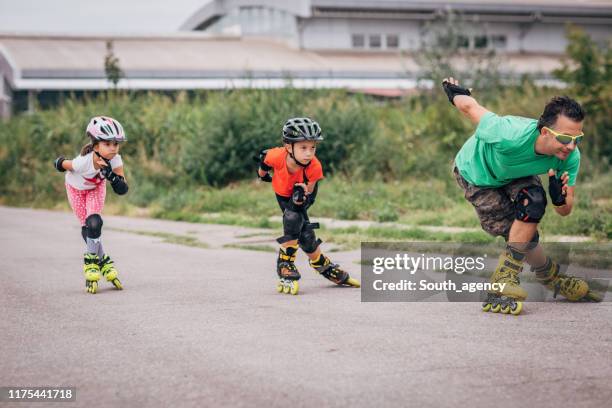chicas aprendiendo patinaje sobre ruedas con el hombre instructor - patín en línea fotografías e imágenes de stock