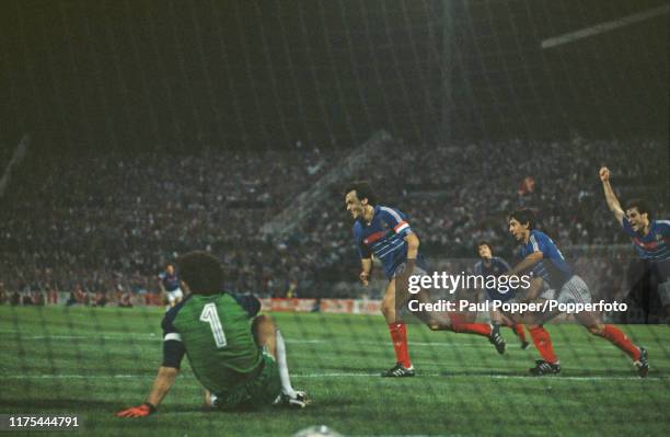 French professional footballer Michel Platini turns away from goal followed by teammate Alain Giresse after scoring the winning goal for the France...