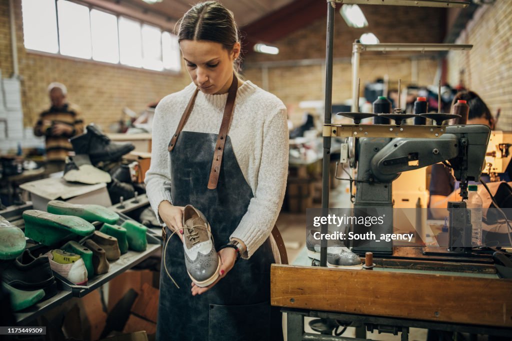 Dame hält einen Lederschuh in Schuhfabrik