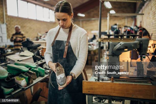 dame hält einen lederschuh in schuhfabrik - shoe factory stock-fotos und bilder
