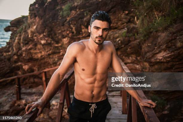 image of a handsome fit man posing near sea - hunky guy on beach stock pictures, royalty-free photos & images