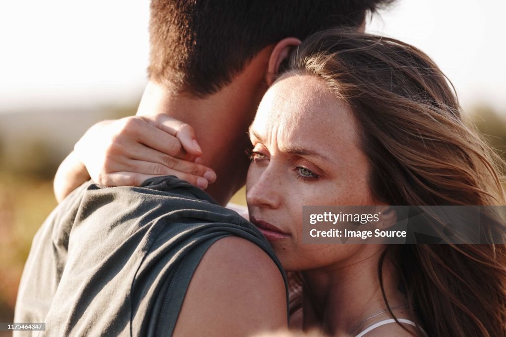 Couple hugging, woman looking worried