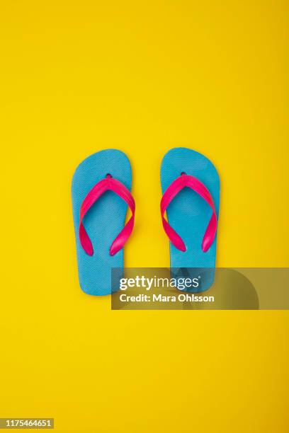 pair of colourful flip-flops on sandy beach - ciabatta infradito foto e immagini stock