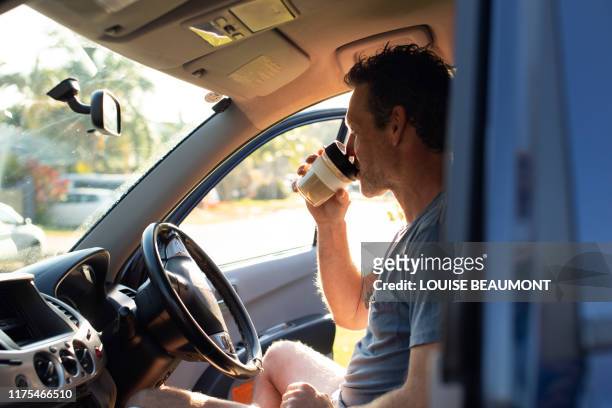 aussie bloke enjoys his morning coffee from an eco travel mug - 車　作業員 ストックフォトと画像