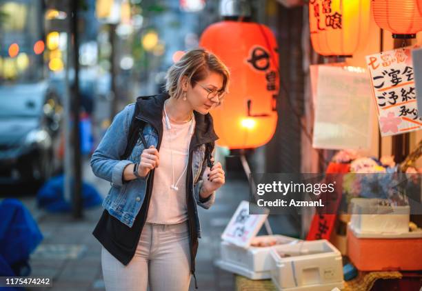 independent caucasian tourist shopping in shinjuku at dusk - japan tourist stock pictures, royalty-free photos & images