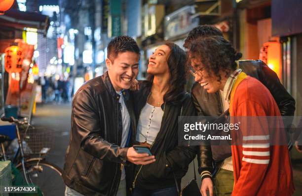 lachende junge freunde checken smartphone in tokio - tokyo travel destinations stock-fotos und bilder