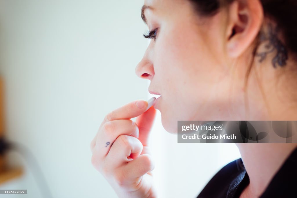Portrait of a woman taking a pill.