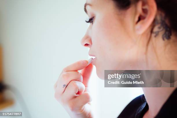 portrait of a woman taking a pill. - comprimido imagens e fotografias de stock
