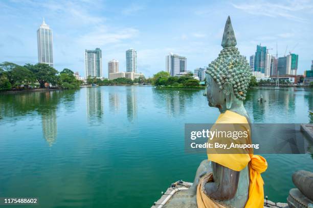 the buddha statue in seema malaka temple on beira lake with beautiful view of colombo skyline in colombo cbd. - colombe stock-fotos und bilder