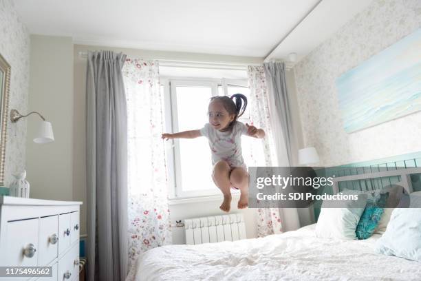 bambino salta felicemente a letto - materasso foto e immagini stock