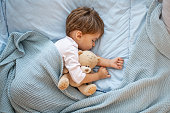 Photo of baby boy sleeping together with teddy bear.