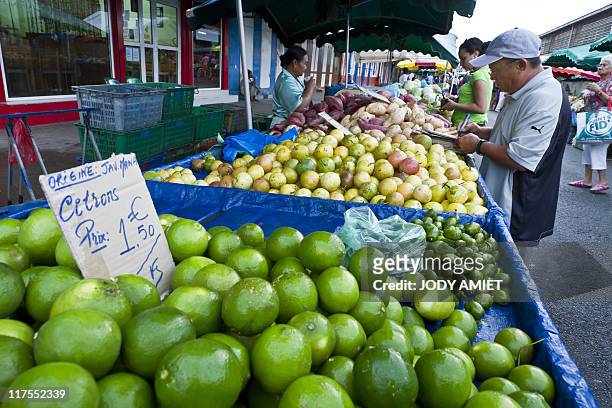 Asia's Hmong ethnic minority diaspora member and market gardener Robert Sion writes prices on placards in front of fruits and vegetables in the...