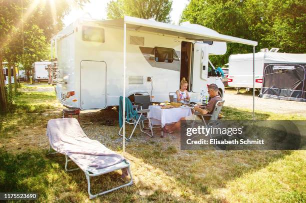 reading couple in front of motorhome - camping family bildbanksfoton och bilder