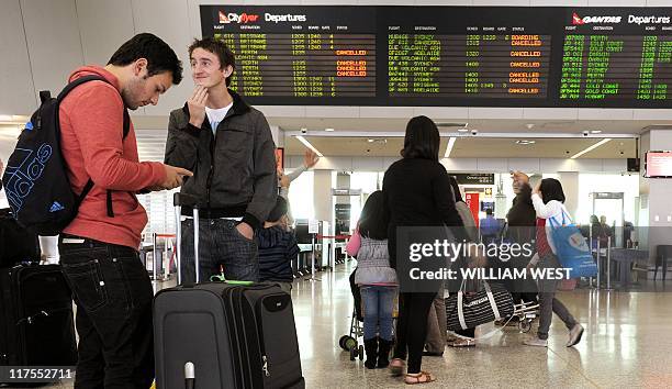 People discuss their options in front of the departures board after the Chilean ash cloud returned to Australia forcing the cancellation of flights...