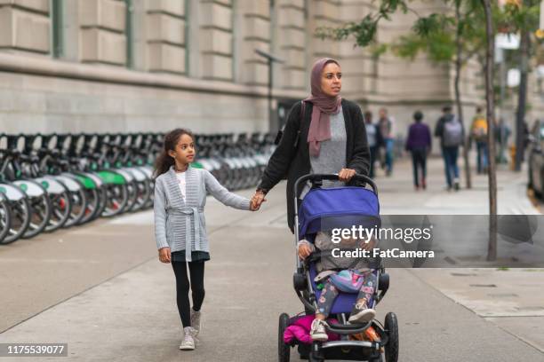 middle eastern woman walking with children in city - pushchair stock pictures, royalty-free photos & images