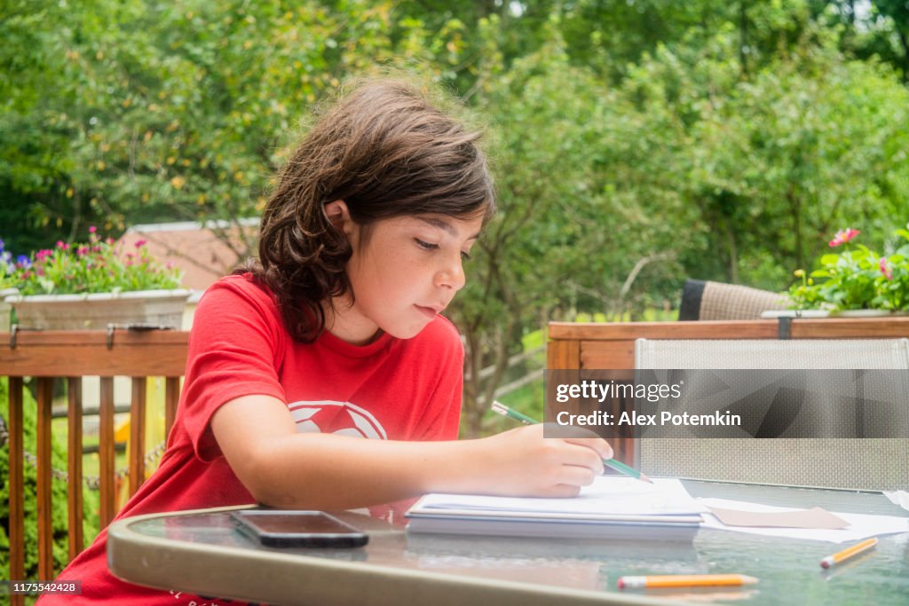 9-years-old boy drawing on a porch.