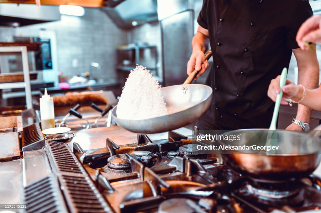 Male Cook Preparing Rice While Female Makes Sauce