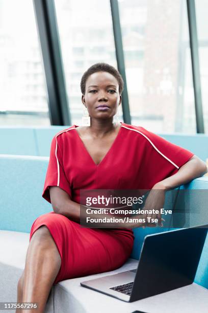 businesswoman using laptop in co-working space - black woman red dress stock pictures, royalty-free photos & images