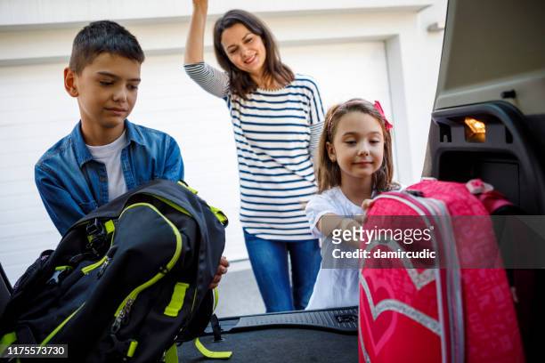 mother and children loading school backpacks into car - car camping luggage imagens e fotografias de stock