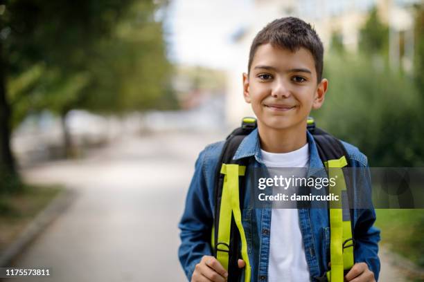 adolescente sorridente con borsa da scuola di fronte a scuola - bambini maschi foto e immagini stock