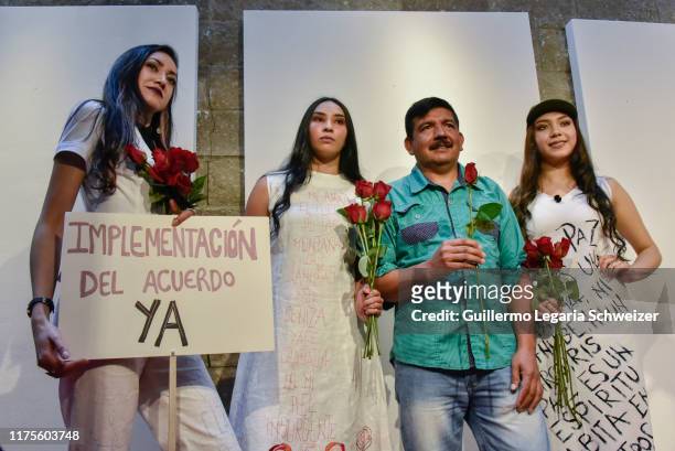 Models pose for pictures holding roses with Jimmy Rodriguez , former FARC rebel, and current designer during the fashion show "Pazarela" as part of...