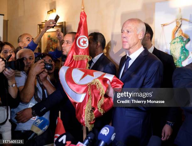 Tunisian presidential candidate Kais Saied kisses the National Flag after the first exit poll in presidential runoff vote suggest he is set to become...