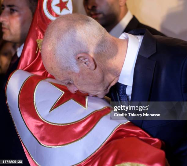 Tunisian presidential candidate Kais Saied kisses the National Flag after the first exit poll in presidential runoff vote suggest he is set to become...